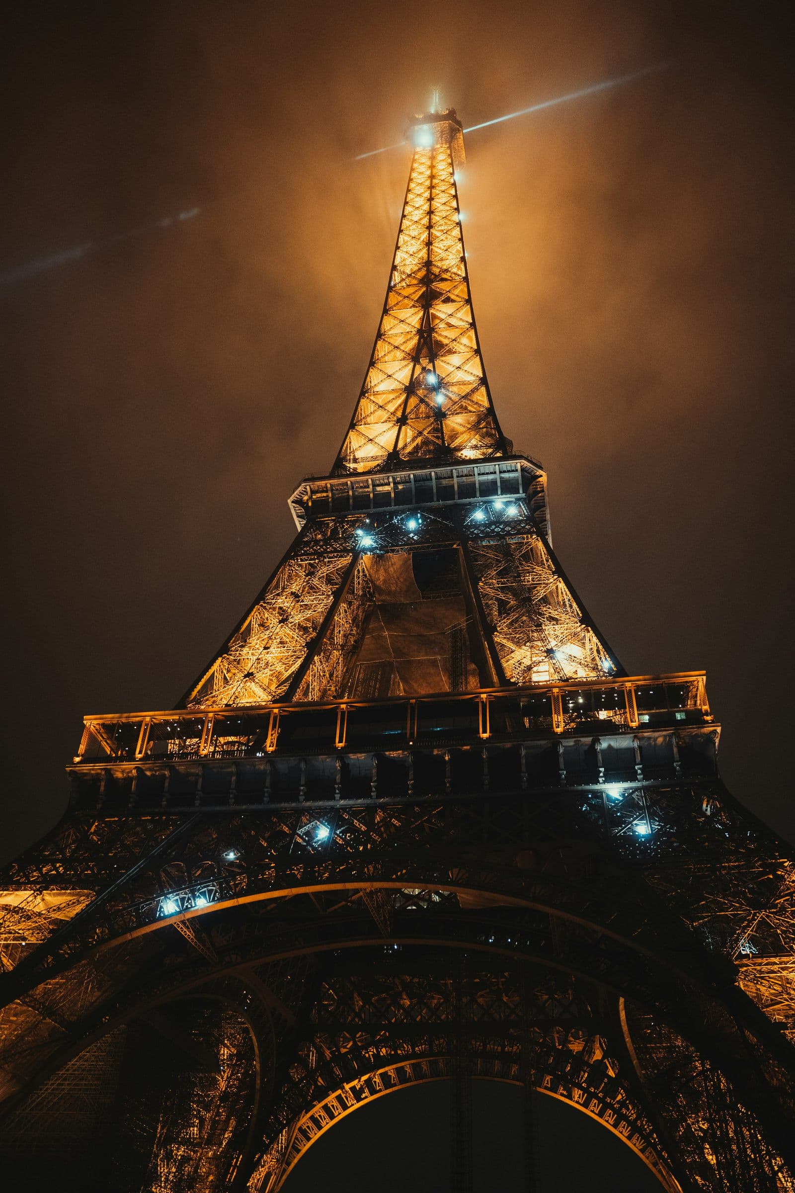 La torre Eiffel iluminada, vista desde abajo, de noche.