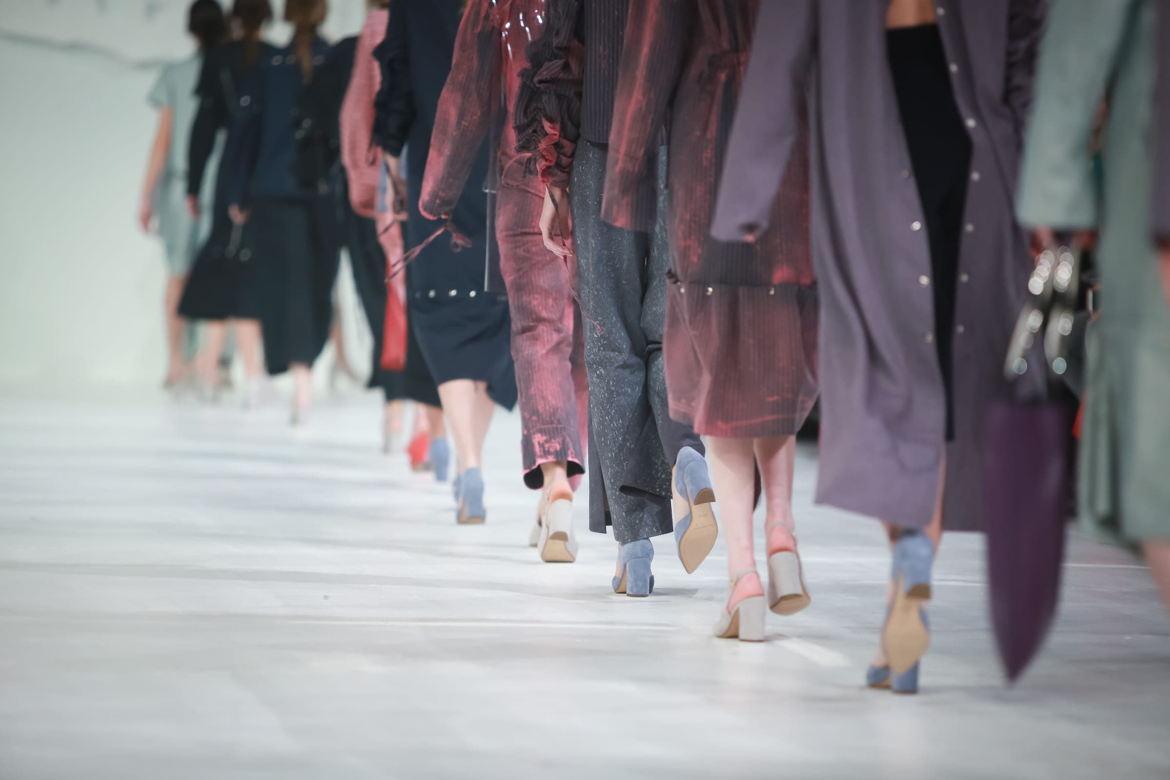 Figures seen from behind on a pale runway, mid-walk.