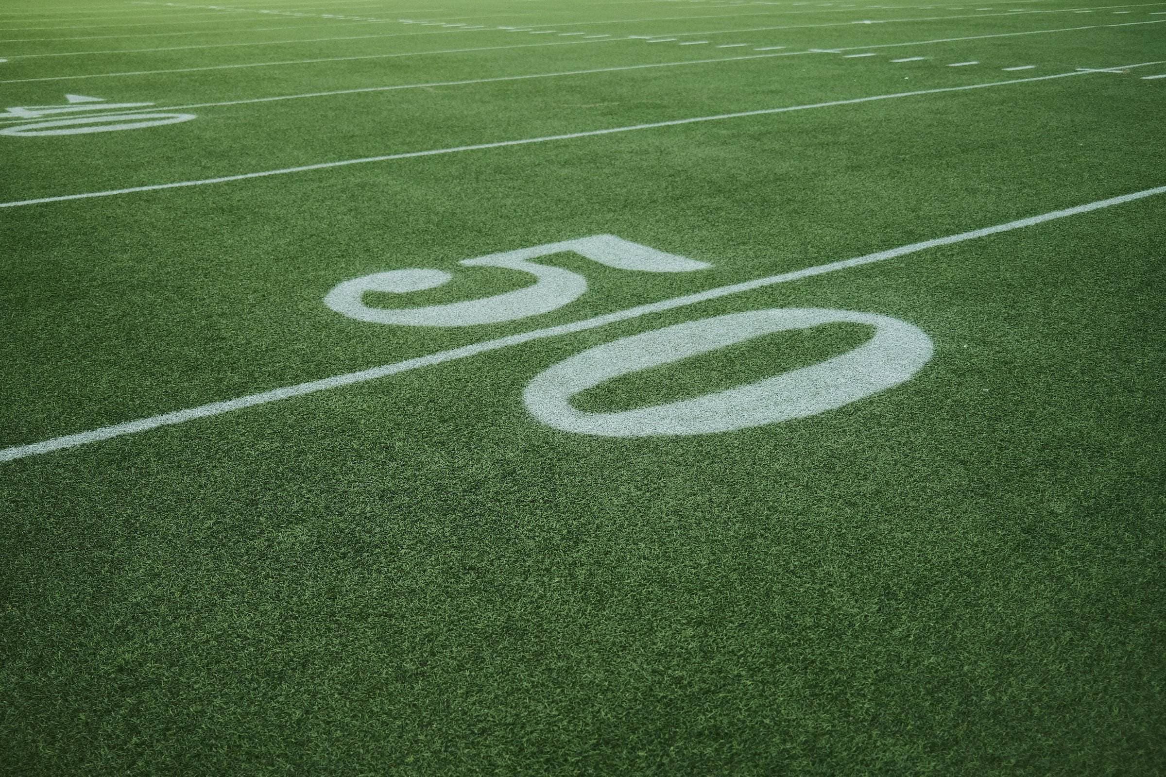 The 50-yard line painted on the turf, seen at ground level.