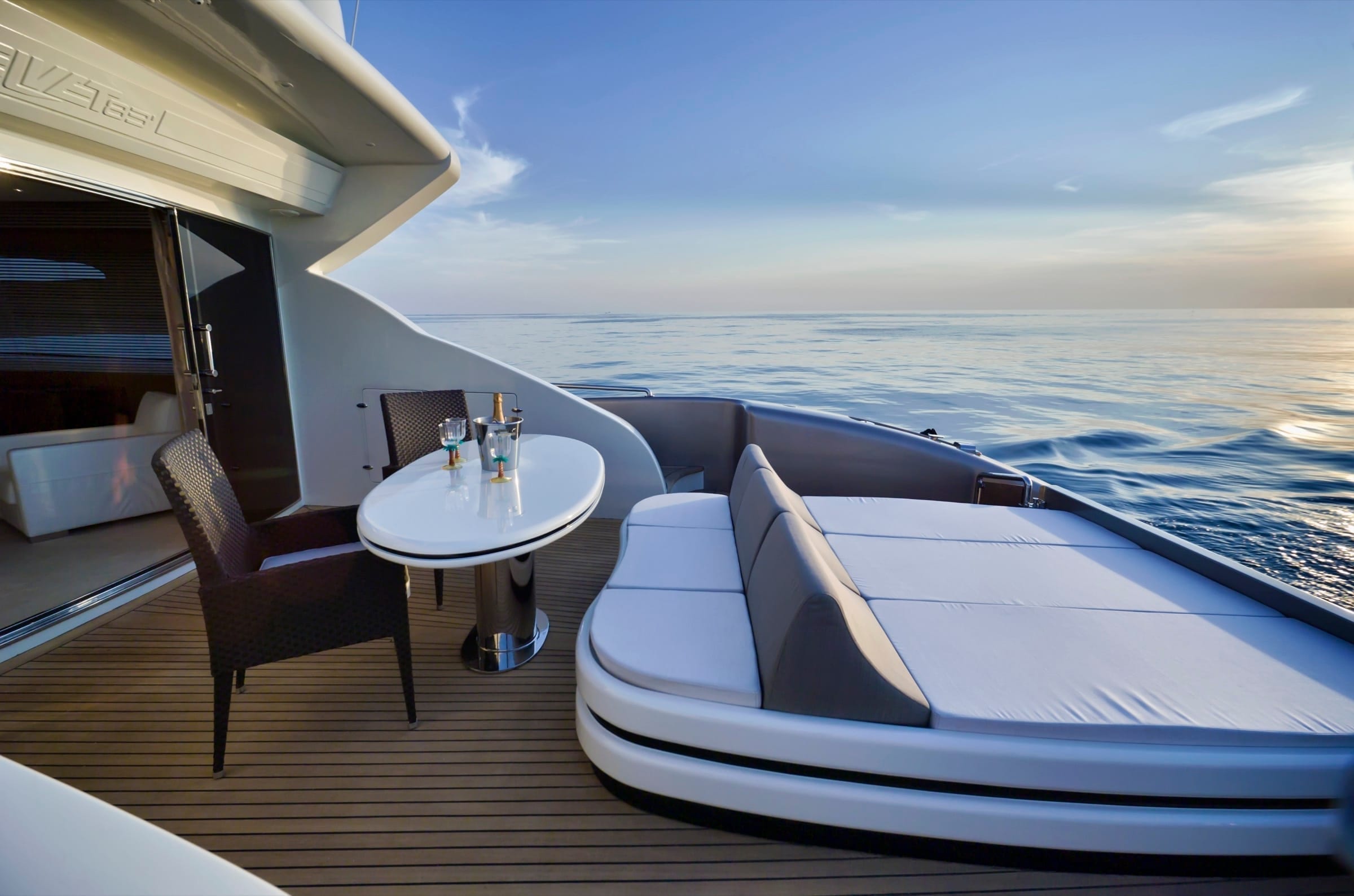 Private deck laid out at dusk, table set facing the horizon, before guests arrive.