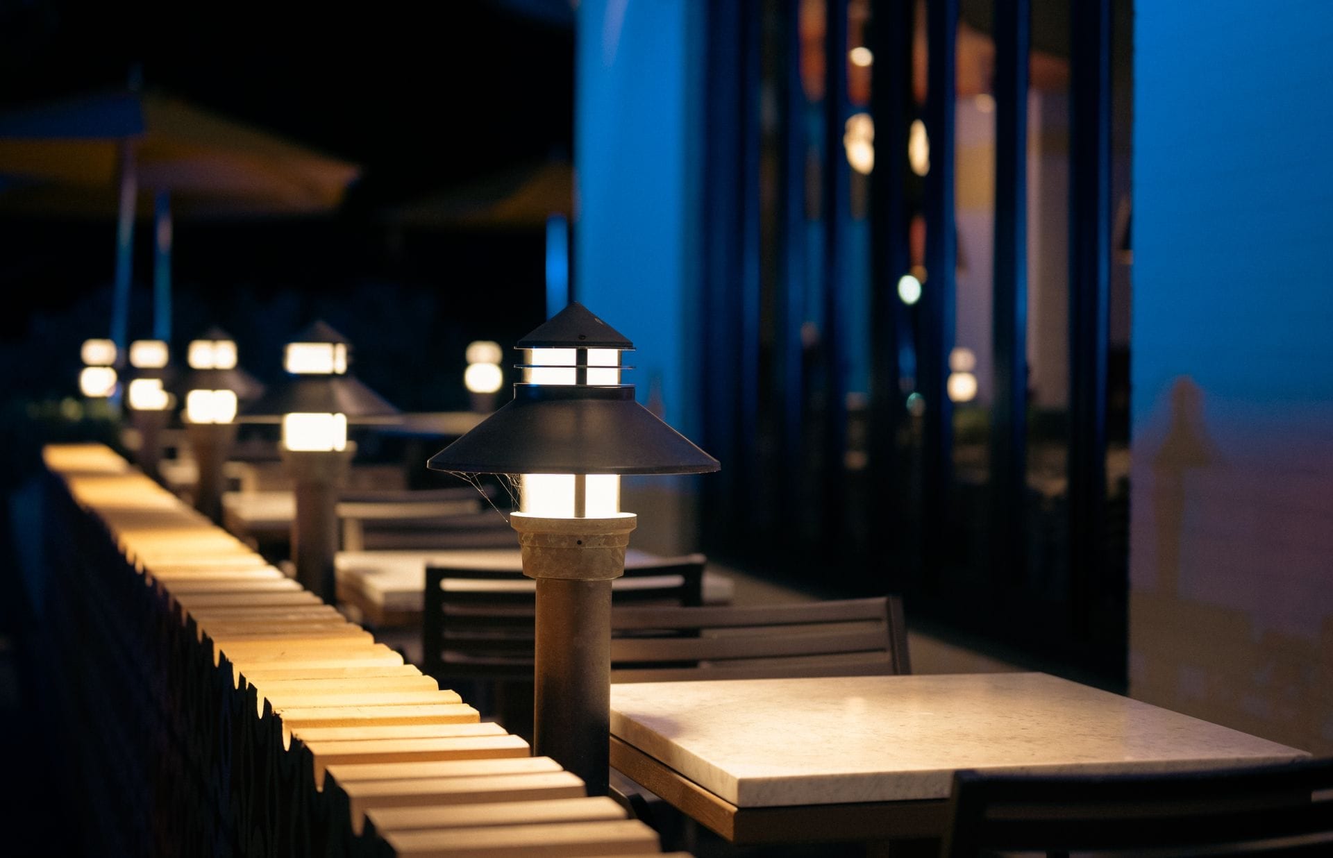 Une terrasse allumée à la tombée du soir, les tables déjà prêtes.