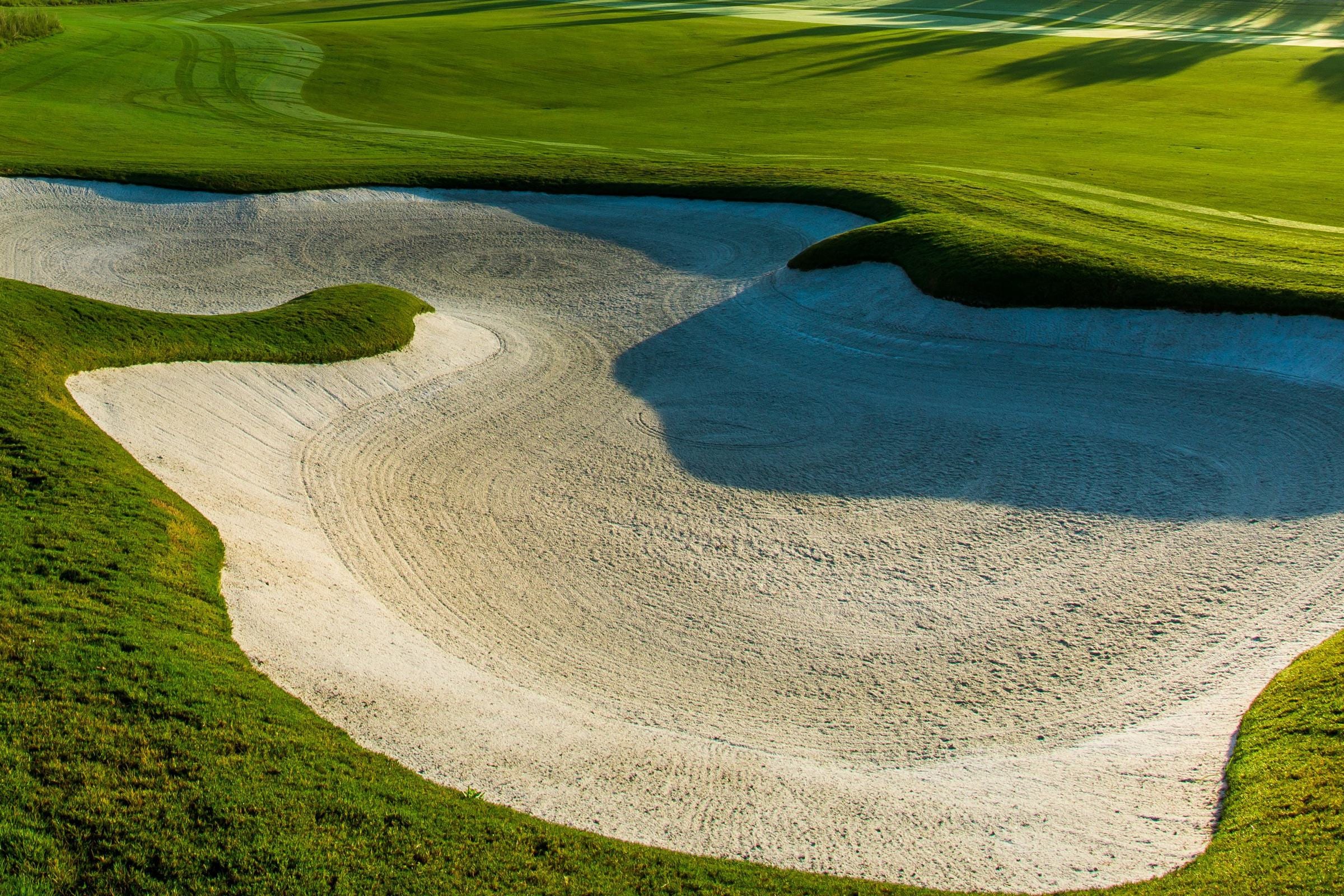 Un bunker de sable blanc fraîchement ratissé, en lumière rasante.