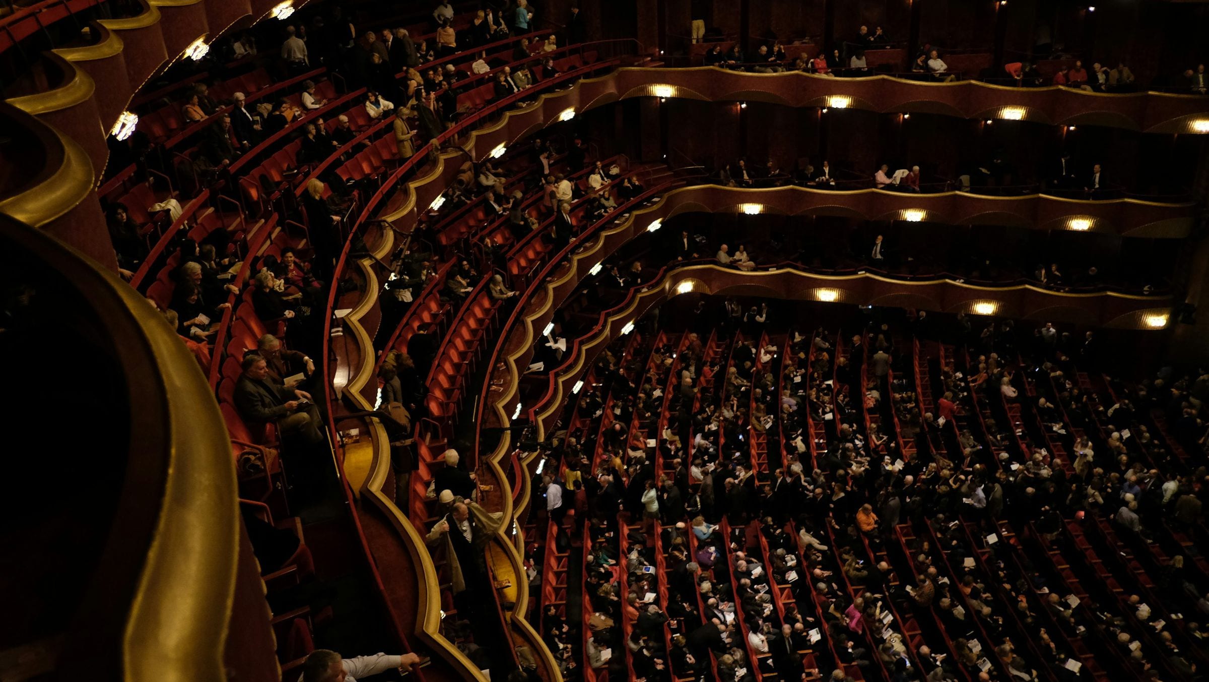 A theatre with gilded balconies, in half-light.