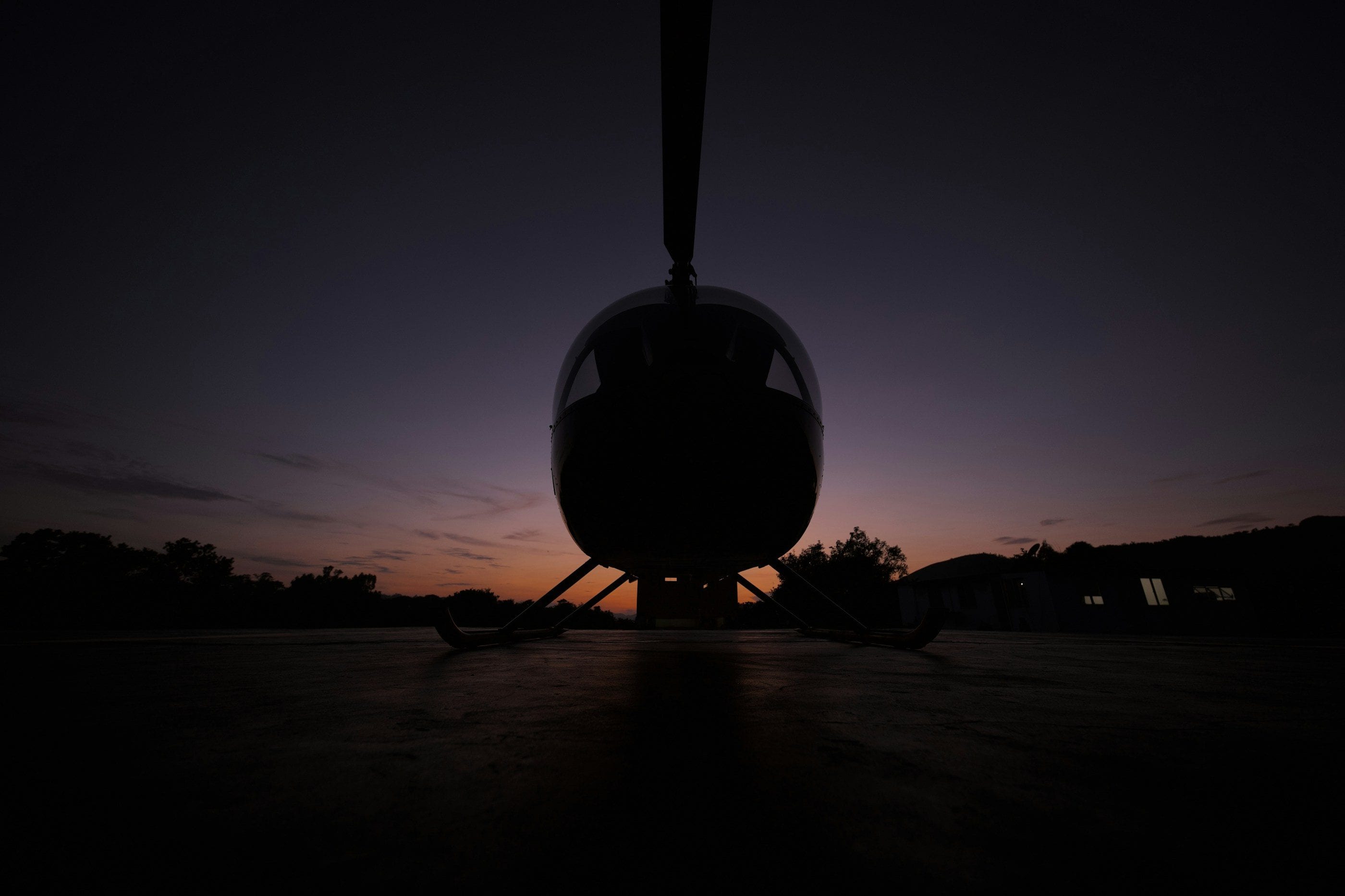 Un hélicoptère en silhouette sur son hélipad, au crépuscule.