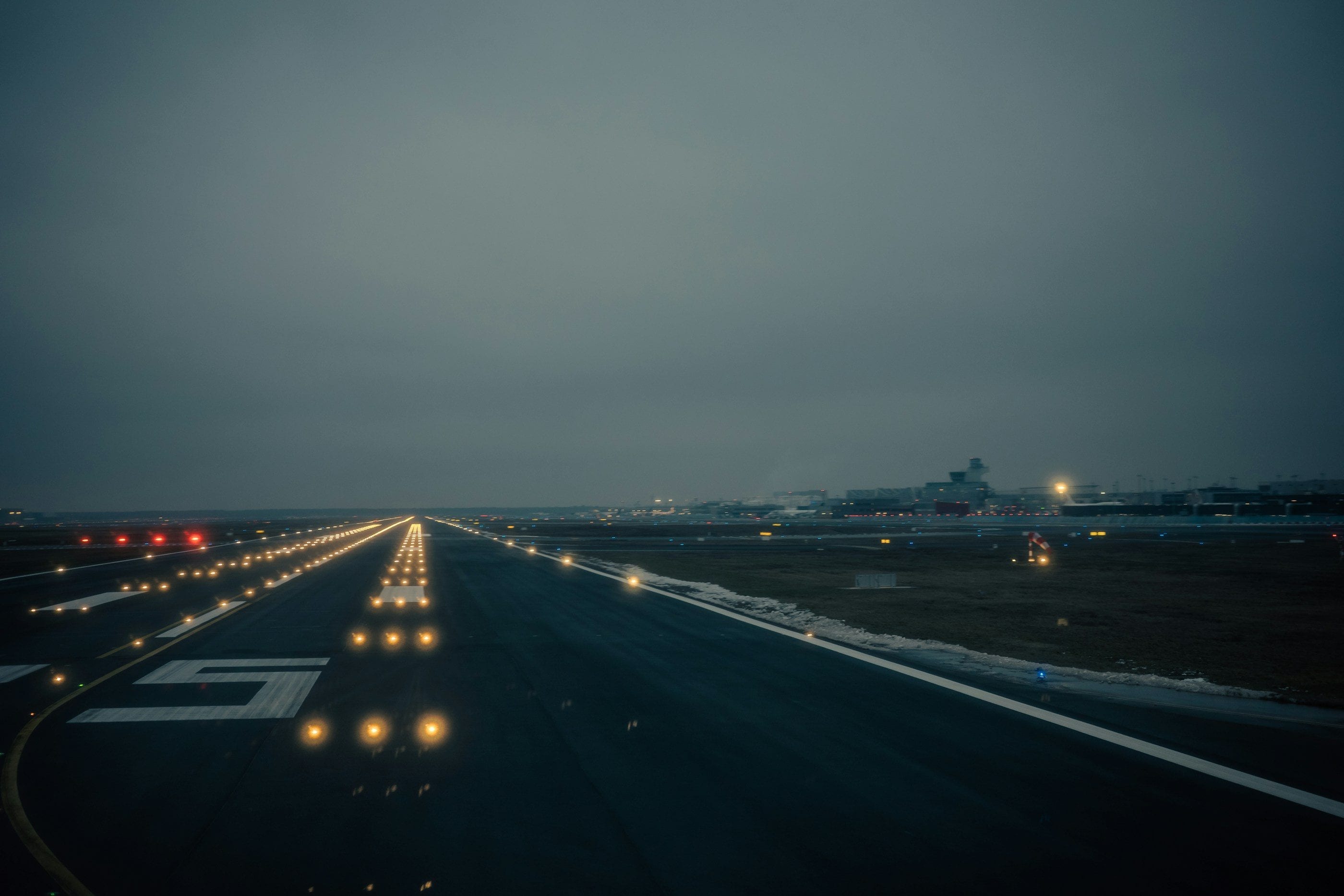 A runway at dusk, its lights glowing all the way to the horizon.
