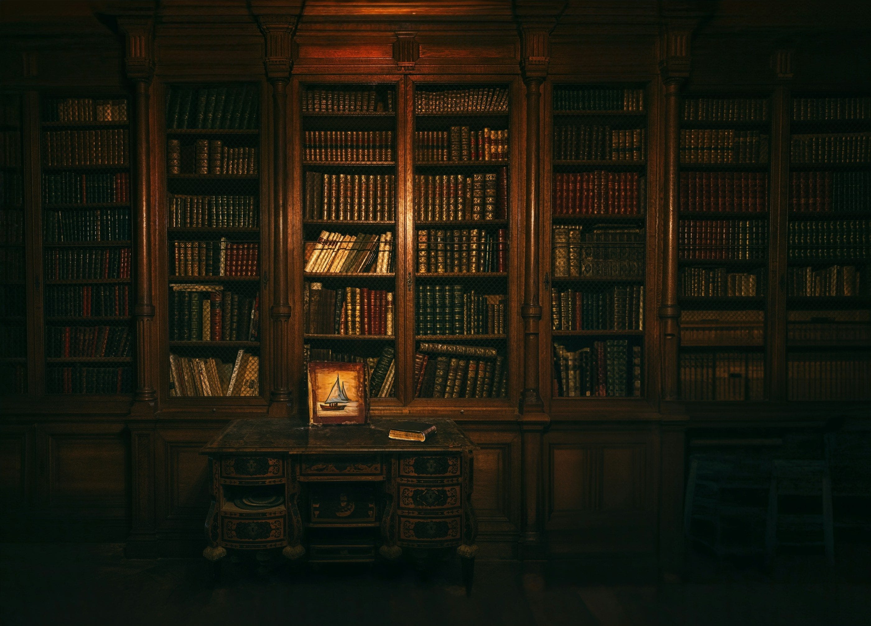 A dark wood-panelled library and a lit antique desk.