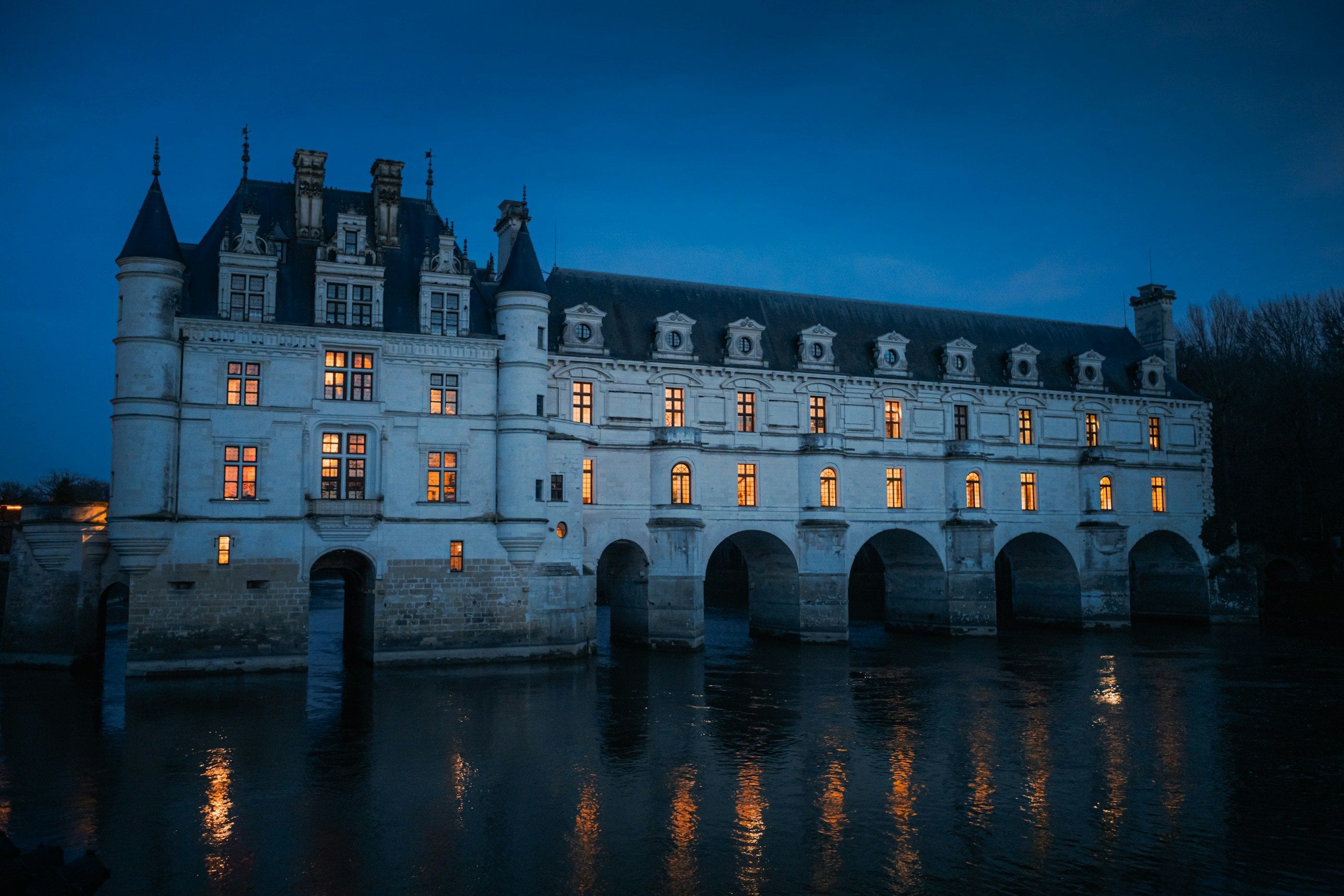 El castillo de Chenonceau a la hora azul, con las ventanas encendidas, reflejado en el Cher.