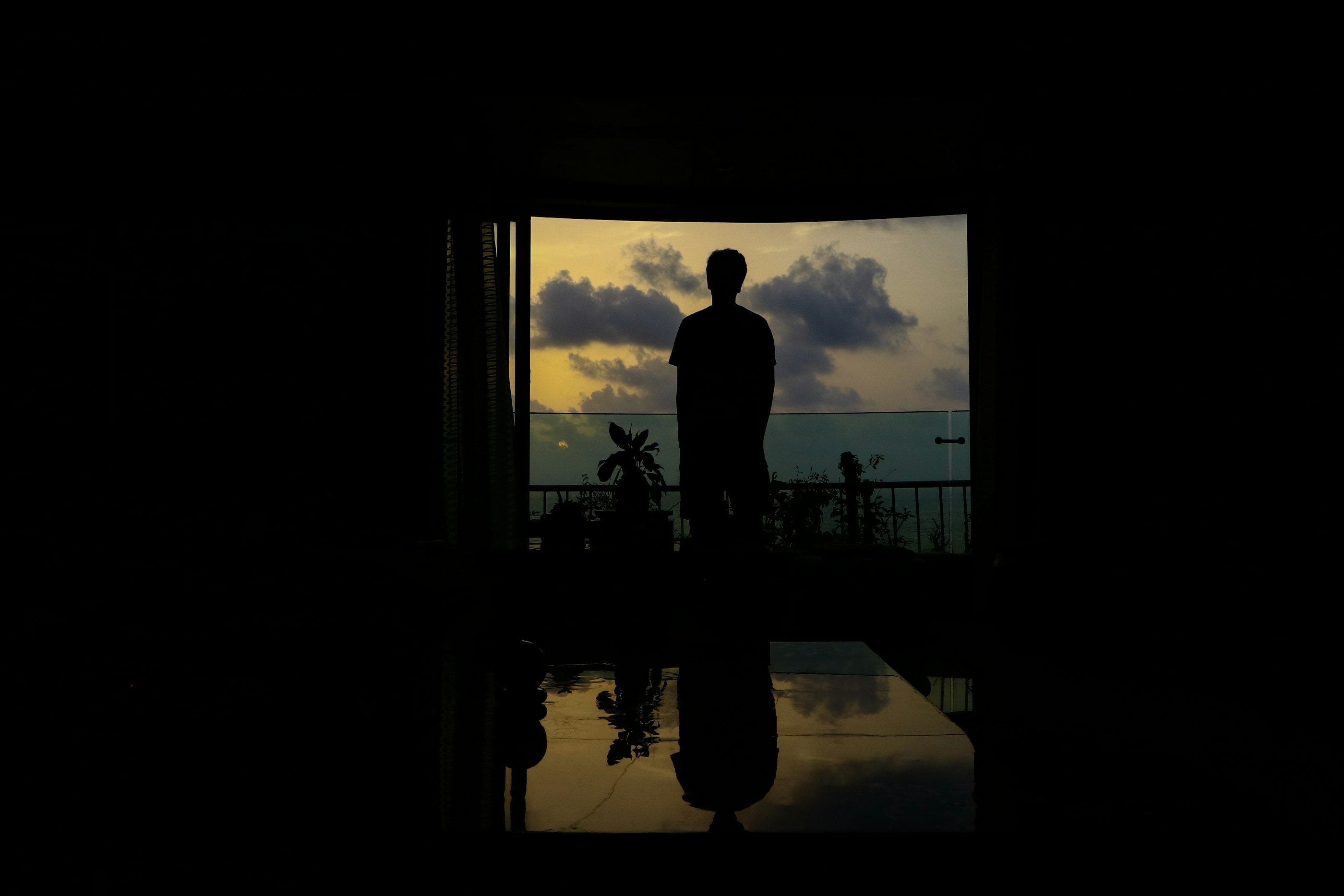 A silhouette on a terrace facing the sea at dusk.