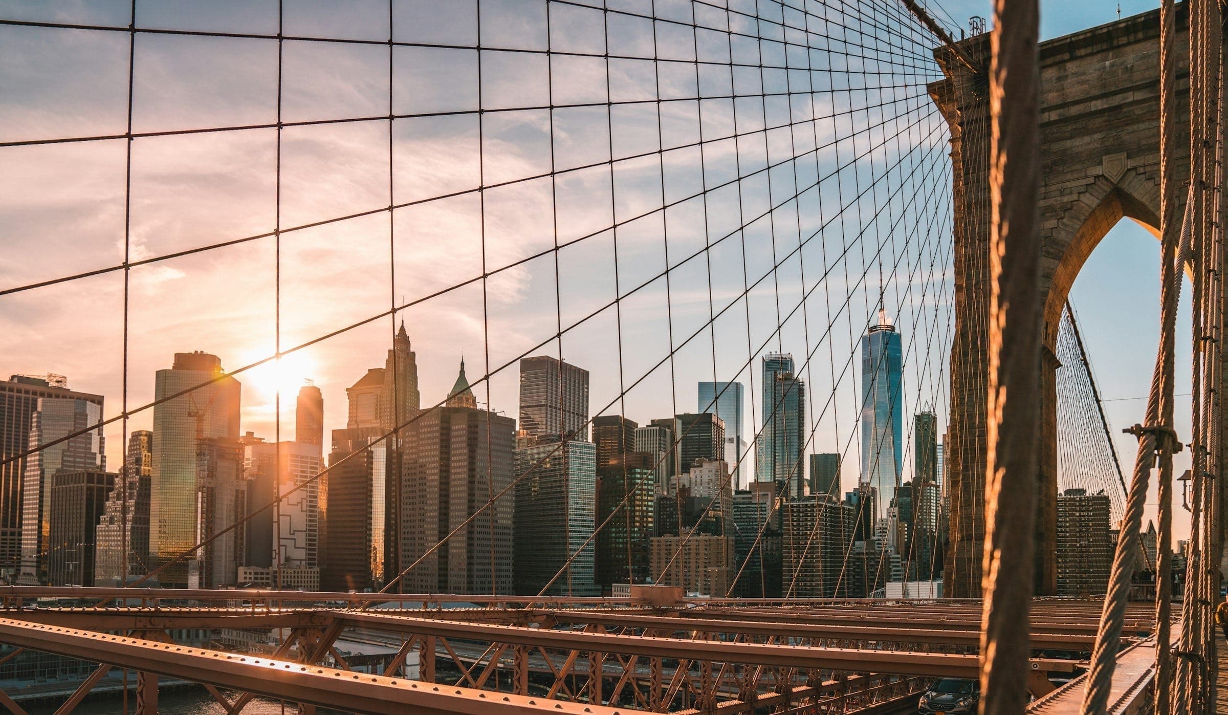 The Brooklyn Bridge at sunset, Manhattan behind its cables.