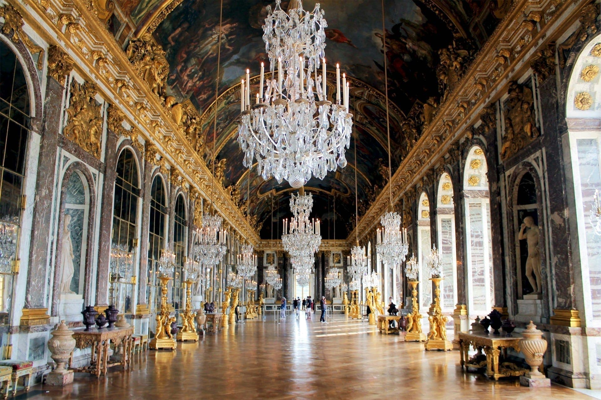 A long gallery of mirrors and gilding beneath crystal chandeliers.