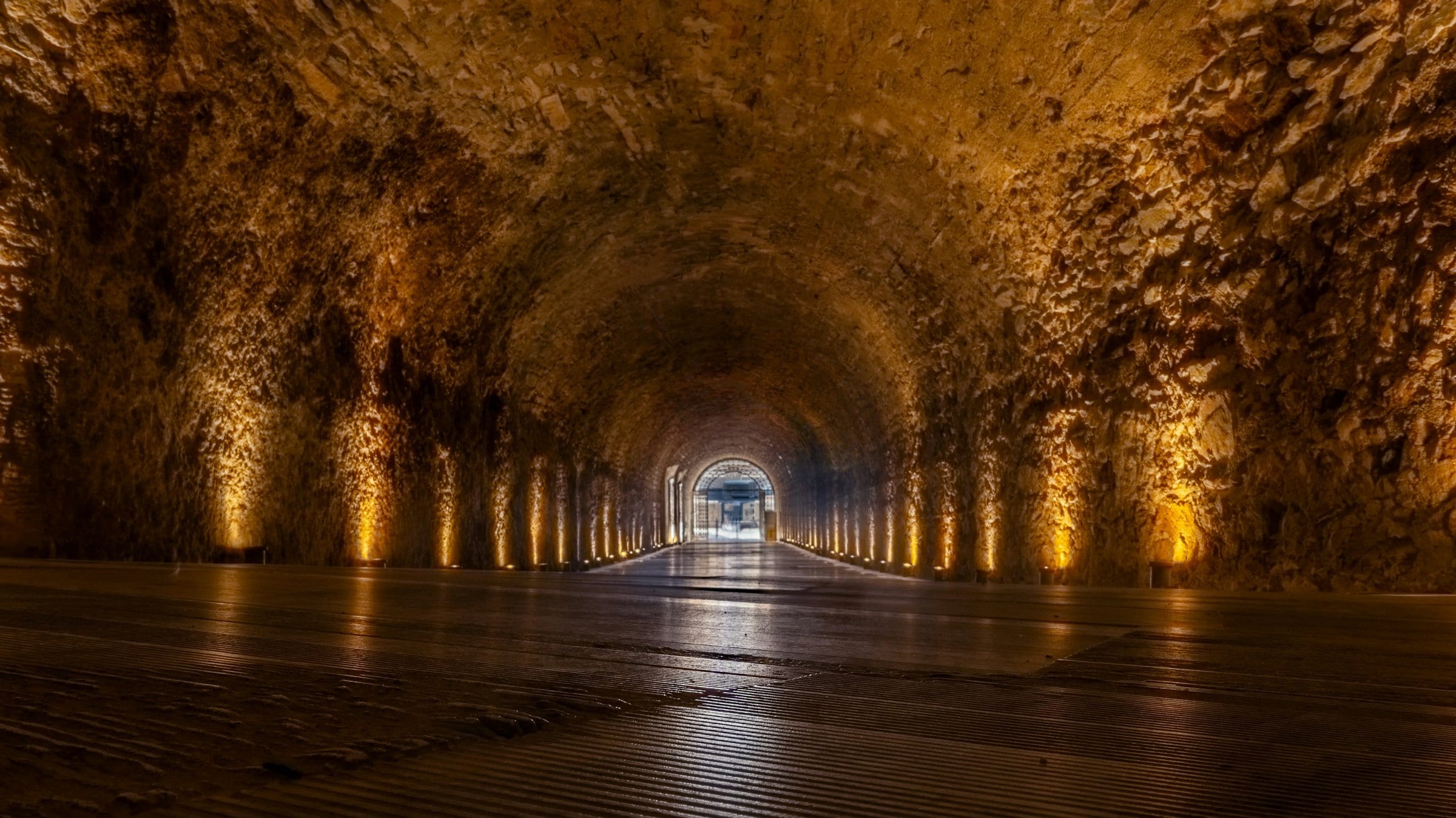 Un tunnel de pierre s'ouvrant sur la lumière d'une arène.