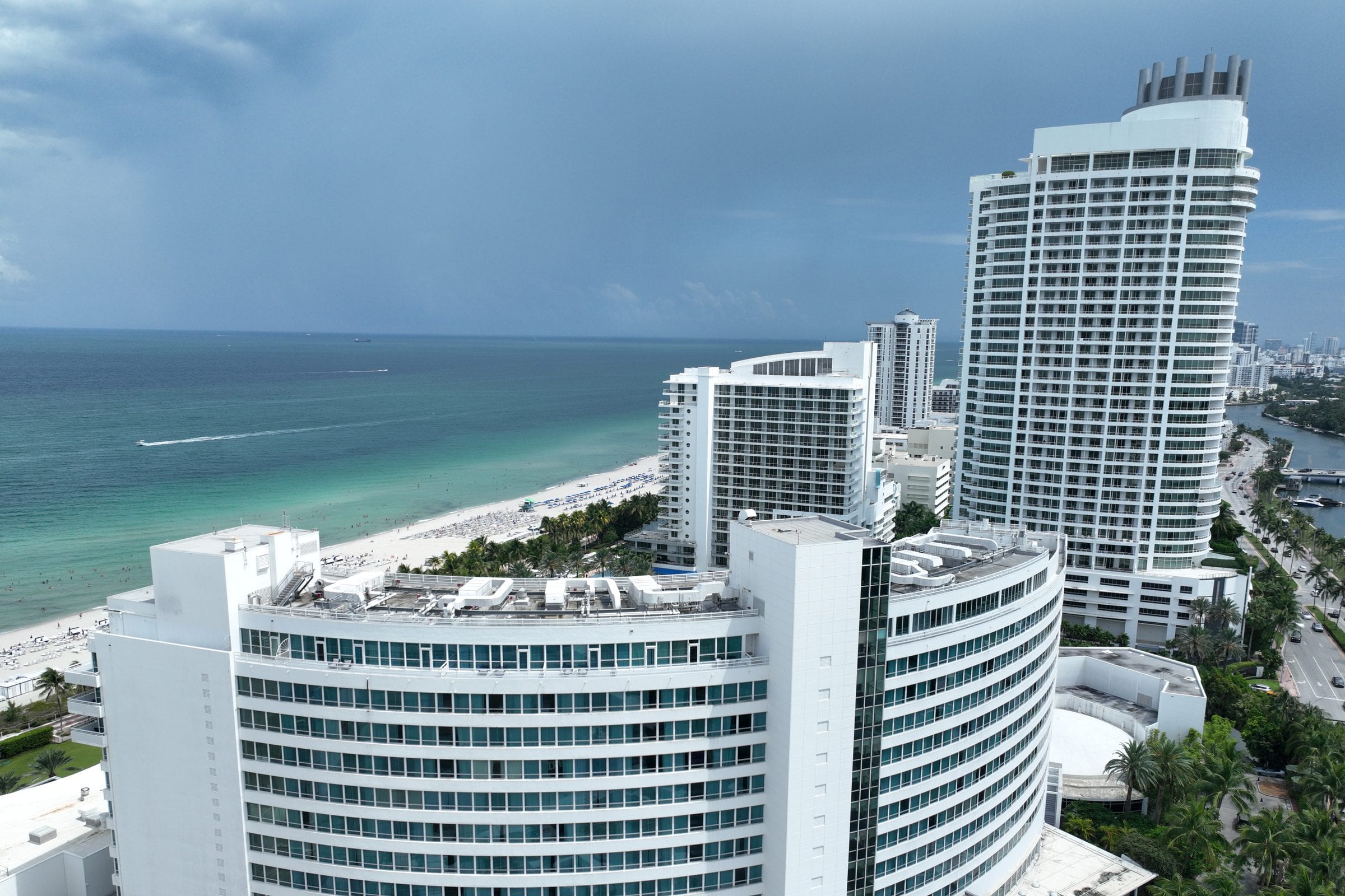 The Miami Beach waterfront from the air, the white curve of the hotels.