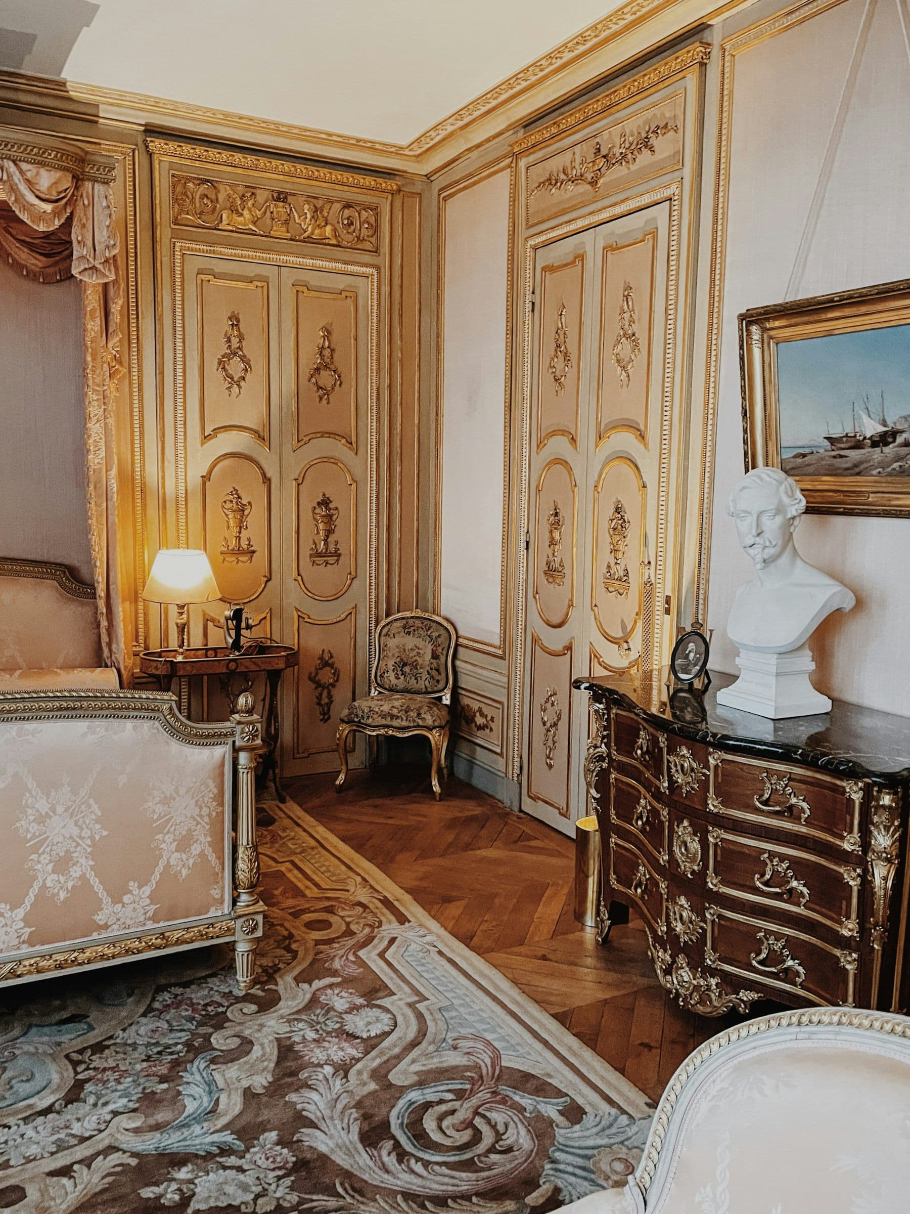 A bedroom with gilded panelling, in the afternoon light.