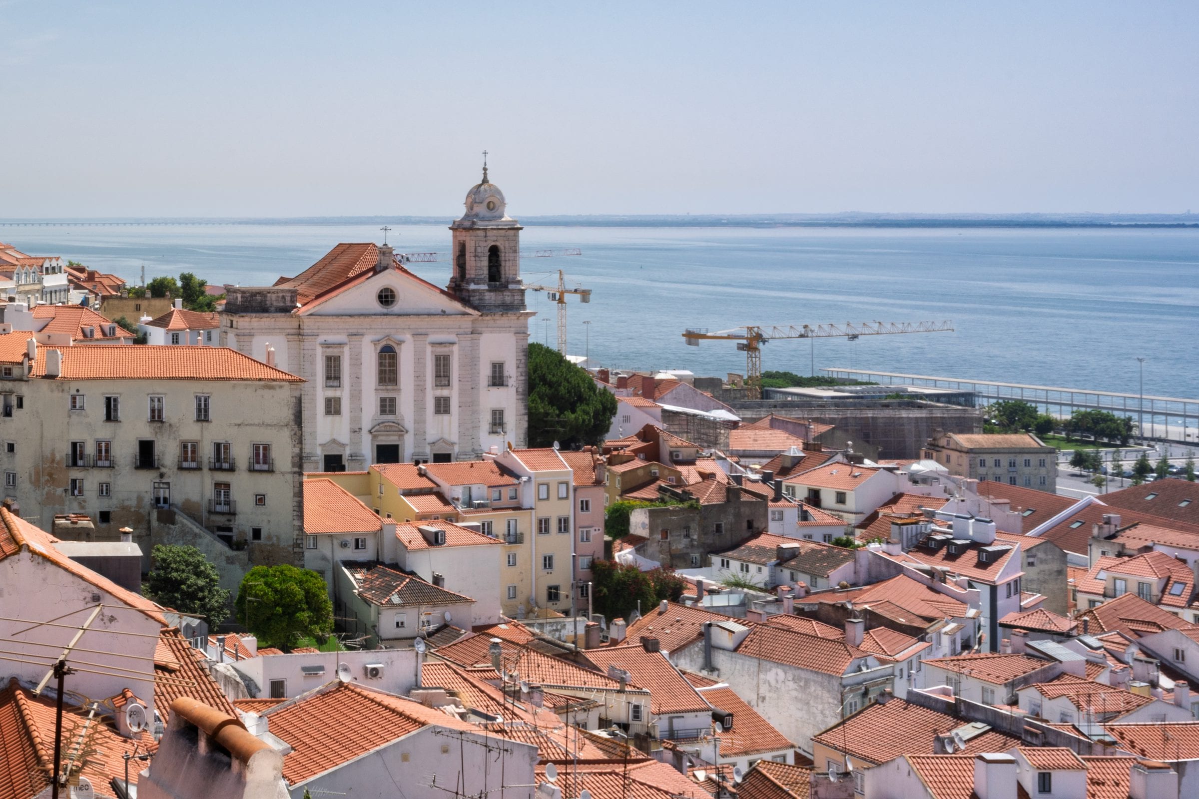 Tiled roofs and pale facades of an old quarter, seen from above.