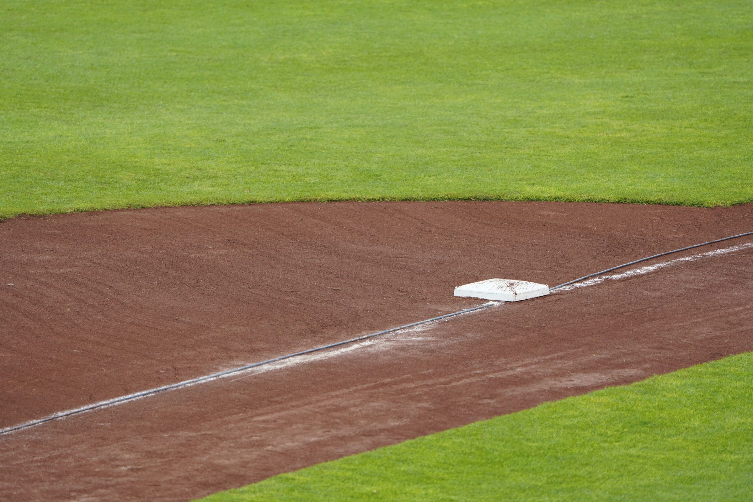 A base set on the chalk line, infield dirt and mown grass.