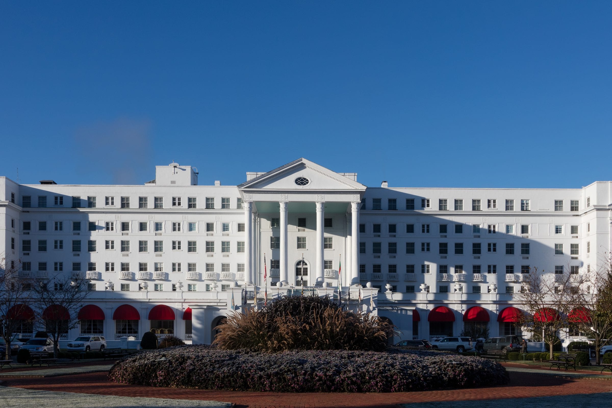The facade of a grand American resort hotel, columns and lawn.